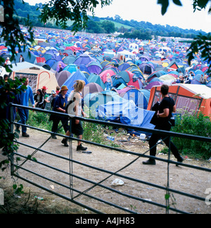 Menschen, die am Glastonbury Festival in Somerset England, Großbritannien, AUF dem Campingplatz Worthy Farm, an Zelten und Toren VORBEIGEHEN, KATHY DEWITT Stockfoto