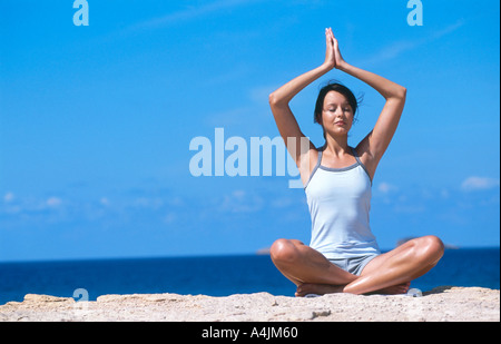 Junge Frau meditieren am Strand Stockfoto