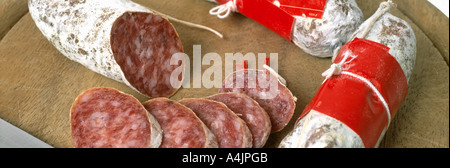 Ganze und Scheiben Salami auf ein Schneidbrett aus Holz Stockfoto