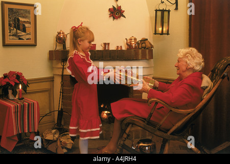 Enkelin teilen Weihnachten präsentiert mit Großmutter zu Hause in der Nähe von Kamin in Schweden Stockfoto