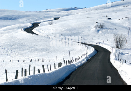 Fahren Sie im Winter Schnee durch eine verschneite Landschaft auf einer gewundenen Landstraße Stockfoto