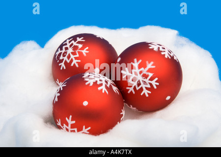 Drei rote Weihnachtskugeln, liegend auf einem Bett aus Baumwolle Stockfoto