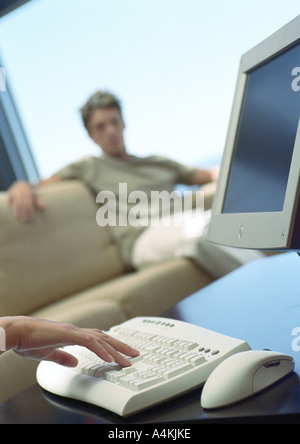 Computer, Mann auf Sofa im Hintergrund Stockfoto