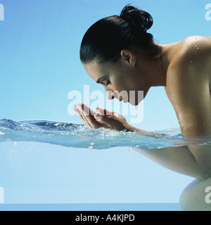 Frau kniend im Wasser, Hände, Gesicht Schröpfen Stockfoto