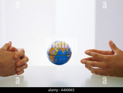 Globus zwischen zwei Paaren von gefalteten Händen Stockfoto