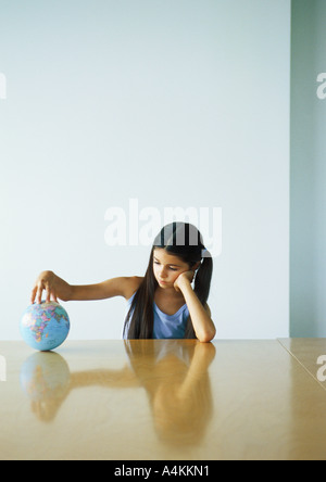 Mädchen sitzen am Tisch mit der Hand auf der ganzen Welt Stockfoto