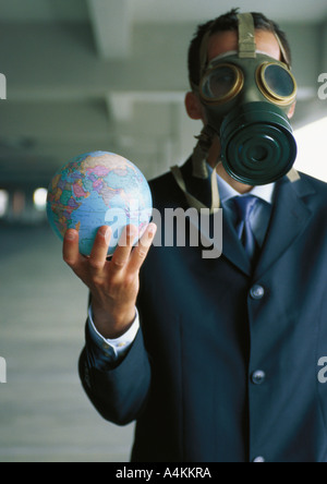 Geschäftsmann Globus in der hand hält, trägt Gasmaske über Gesicht Stockfoto