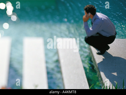 Mann auf Gehweg in der Nähe von Wasser, mit Handy Stockfoto