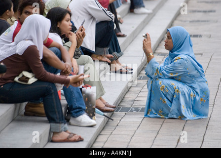 Eine muslimische Frau tragen Hijab fotografiert ihre Freunde mit einer digitalen Kamera in Kuala Lumpur Stockfoto