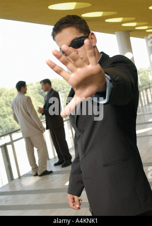 Leibwächter an Hand heraus in die Kamera während der beiden Männer Converse im Hintergrund Stockfoto