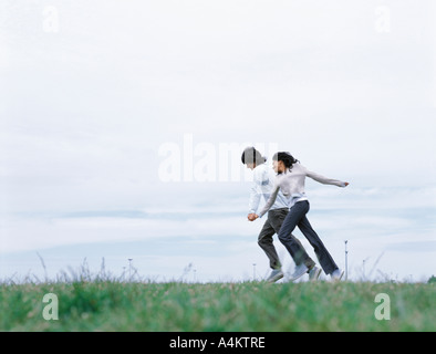 Junger Mann und Frau Hand in Hand und laufen auf dem Rasen Stockfoto