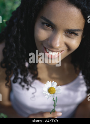 Junge Frau hält Gänseblümchen, Porträt Stockfoto
