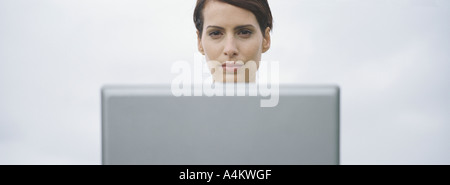 Frauenkopf über Rand des Computerbildschirms, Himmel im Hintergrund zu sehen Stockfoto