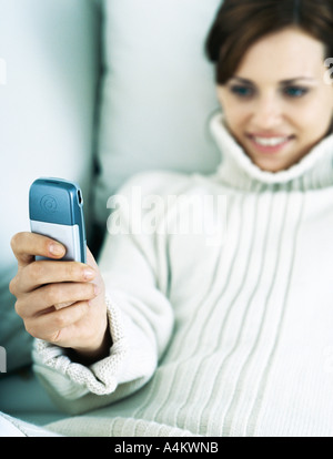 Frau lehnt sich zurück auf Kissen Handy halten und Lächeln Stockfoto