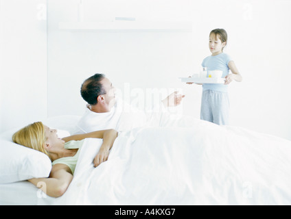 Mädchen bringen Eltern Frühstück im Bett Stockfoto