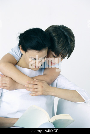 Frau und Sohn Buch zu lesen, junge mit Armen um Frau, über die Schulter schauen Stockfoto