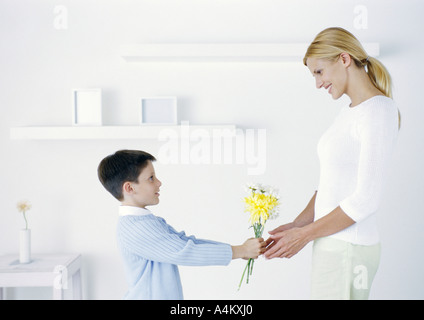 Junge hält sich Blumen, Mutter Stockfoto