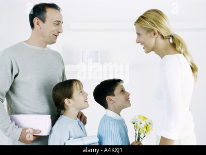 Mann mit jungen und Mädchen konfrontiert Frau mit Geschenken und Blumen Stockfoto