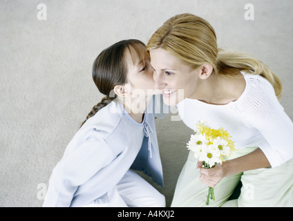 Frau mit Blumenstrauß, Mädchen, die ihre Wange küssen Stockfoto