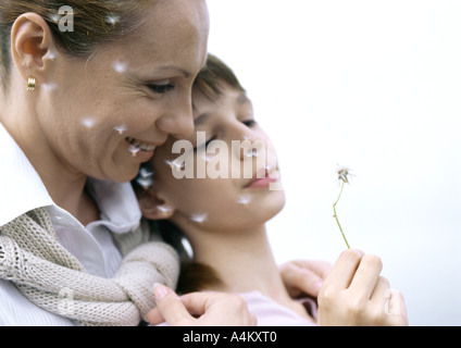 Mutter mit Mädchen bläst Löwenzahnsamen, close-up Stockfoto