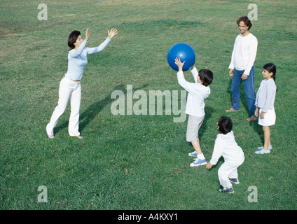 Eltern mit jungen und Mädchen Ballspiele auf dem Rasen, in voller Länge Stockfoto