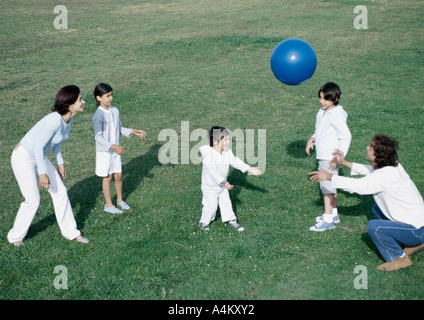 Eltern mit jungen und Mädchen Ballspiele auf dem Rasen, in voller Länge Stockfoto