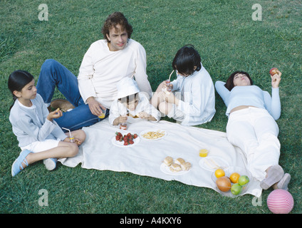 Eltern mit jungen und Mädchen mit Picknick auf der Wiese Stockfoto