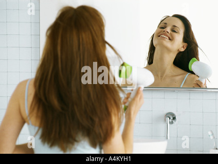 Frau trocknen Haare vor Spiegel Stockfoto