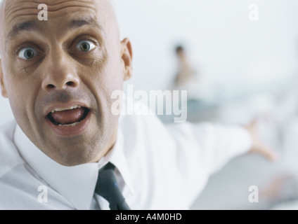 Geschäftsmann mit Augenbrauen angehoben und Mund öffnen zeigt in Hintergrund, Nahaufnahme Stockfoto
