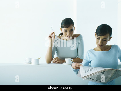 Zwei Frauen, die die Kaffeepause, einer Lesung Zeitung, Rauchen eine Stockfoto