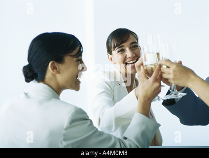 Geschäftsleute, die Gläser klirren und lächelnd Stockfoto