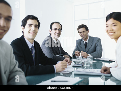 Geschäftsleute, die an Tisch, lächelnd in die Kamera Stockfoto