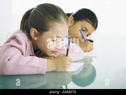 Zwei Mädchen sitzen am Tisch schreiben Stockfoto