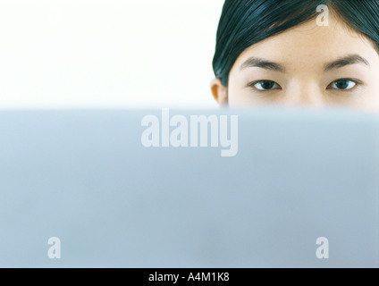 Frau, die über den Rand des Bildschirms, Blick in die Kamera Stockfoto