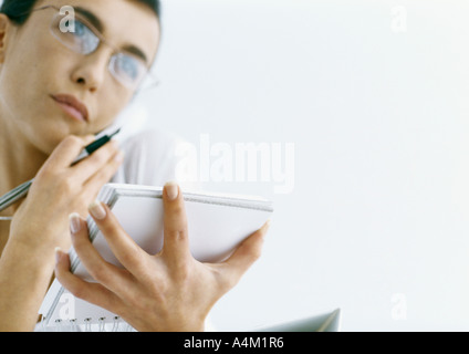 Frau am Telefon mit Notizblock und Stift Stockfoto