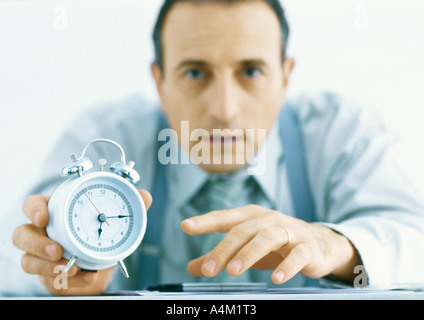 Mann hält Wecker, konzentrieren sich auf Hände und Uhr im Vordergrund Stockfoto