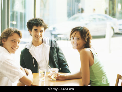 Gruppe von jungen Leuten am Tisch in cafŽ, in die Kamera Lächeln Stockfoto