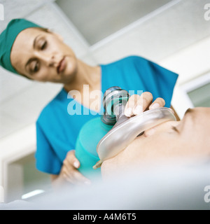 Ärztin mit Sauerstoffmaske über Gesicht des Patienten Stockfoto