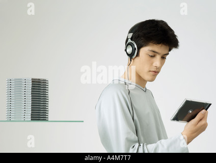 Junger Mann hören, Kopfhörer, Blick auf cd Stockfoto