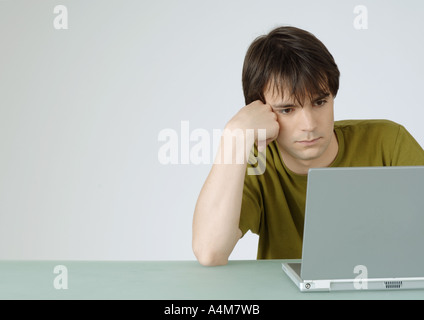 Junger Mann mit Laptop, stützte sich auf Ellbogen Stockfoto