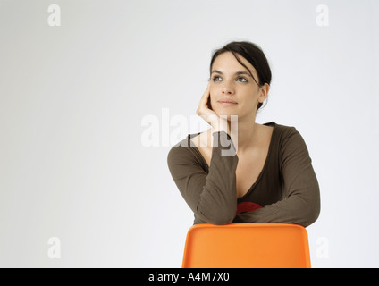 Junge Frau sitzt hinten am Stuhl, Porträt Stockfoto