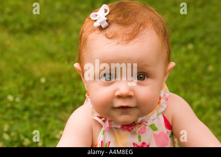Eine ansprechende Babymädchen mit roten Haaren in die Kamera schaut Stockfoto