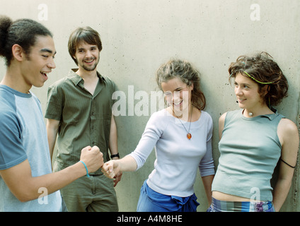 Vier junge Freunde stehend nahe bei der Wand, die Fäuste zwei berühren Stockfoto
