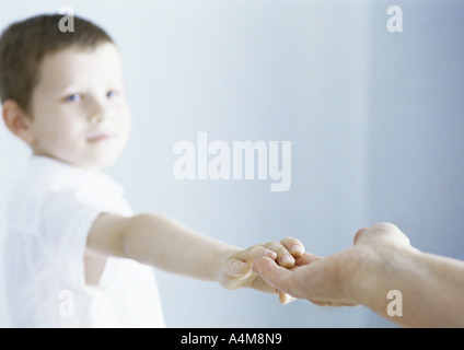 Junge Annäherung an Hand des Erwachsenen zu berühren Stockfoto