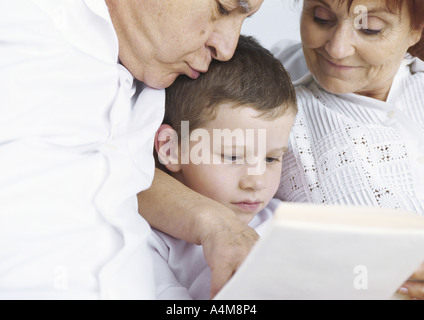 Großeltern mit Enkel lesen Stockfoto