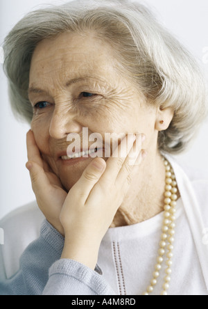 Mädchen hält Großmutter Gesicht, beschnitten Stockfoto