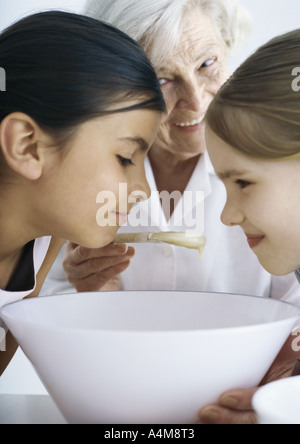 Mädchen beugte sich über die Schüssel, Großmutter Lächeln im Hintergrund Stockfoto