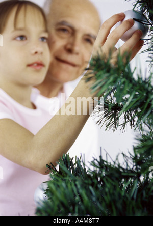 Mädchen und Großvater schmücken Weihnachtsbaum Stockfoto