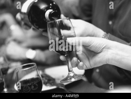 Man gießt Wein für Frau Stockfoto