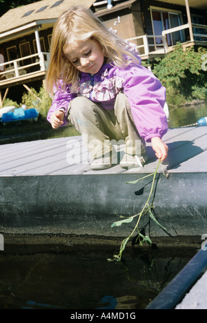 MÄDCHEN (CA. 3-5 JAHRE.) EINTAUCHEN IN WASSER VERZWEIGEN Stockfoto